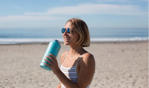 woman drinking water on the beach